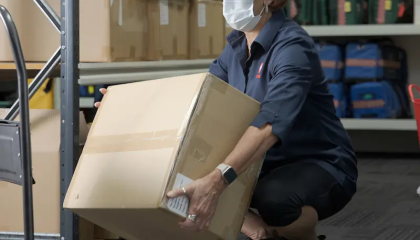 Woman squatting down with a straight back, to pick up a box 